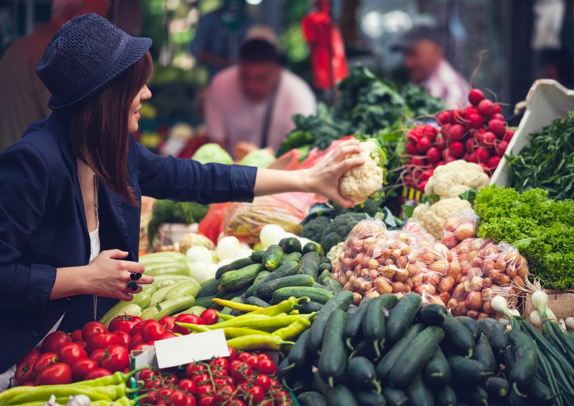 A woman is holding some vegetables at the market