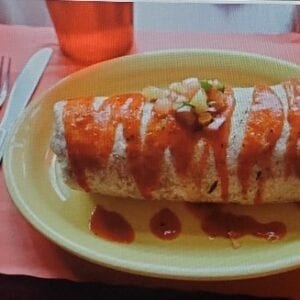 A burrito with sauce on top of it.