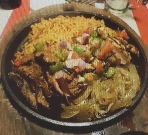 A pan of food on the table with rice and meat.