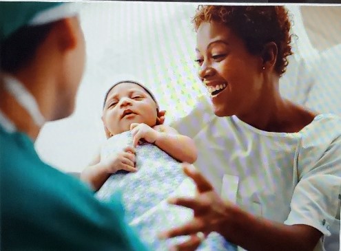 A woman holding a baby and talking to two men.