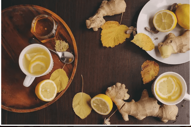 A wooden table with tea and lemon slices on it.