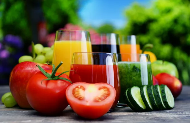 A table with several glasses of juice and vegetables.